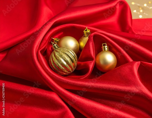 Golden Christmas baubles in deep red satin folds.