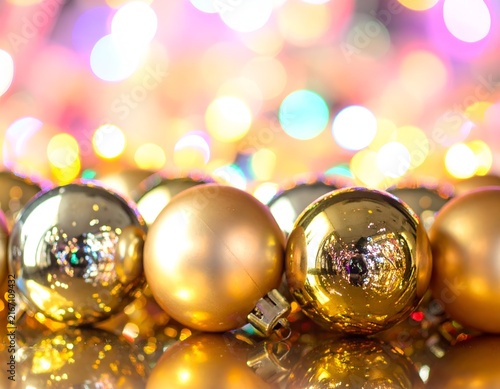 Golden Christmas ornaments in a row with warm bokeh.