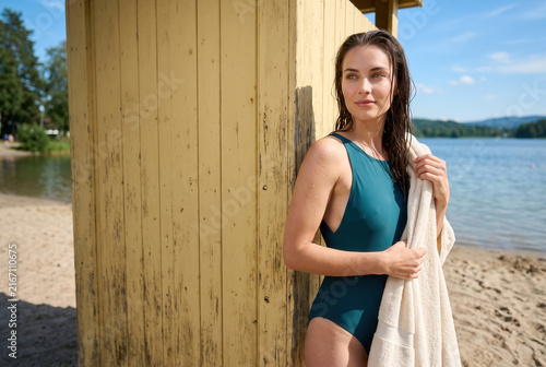Woman in Swimsuit with Towel Beside Sunny Lakeside Beach