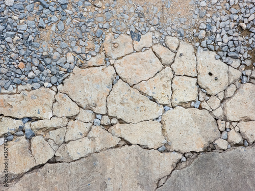 Konstfotografi Broken cracked concrete pavement transition to loose gravel stones on ground sur