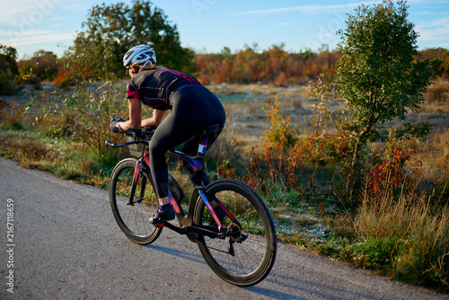 Konstfotografi Female Cyclist Riding Road Bike on Country Road at Sunrise Training for Fitness