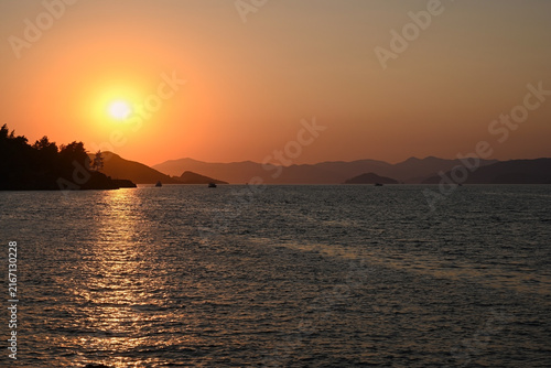 Shining golden sunset over the Mediterranean Sea with silhouettes of mountains on the horizon