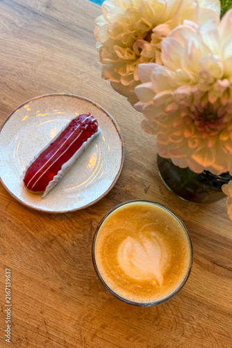 Foto Coffee with eclair dessert and flowers on a wooden table during the day