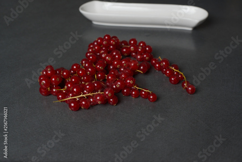 Obraz na płótnie Vibrant red currants rest on a sleek, dark surface