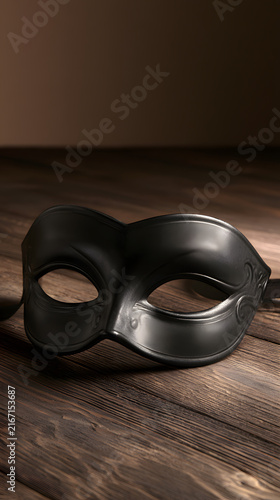 Elegant black masquerade mask on rustic wooden surface