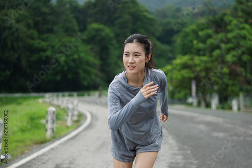 Young Asian woman jogging on road during outdoor workout