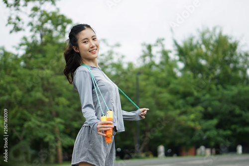 Portrait of happy Asian woman holding skipping rope in park