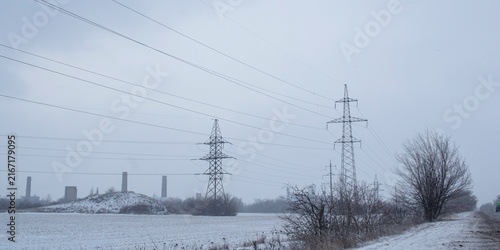 Фотография High-voltage power transmission pylon in a snowy industrial landscape