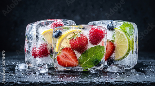 High-end conceptual food photography of colorful fruits and berries partially frozen inside transparent blocks of crystal-clear ice 