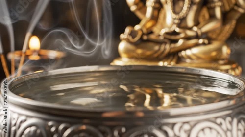 Water Droplets Falling into Sacred Bowl with Incense Smoke and Statue