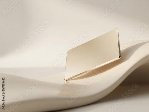 Blank gold credit card emerging from a smooth abstract white wave surface