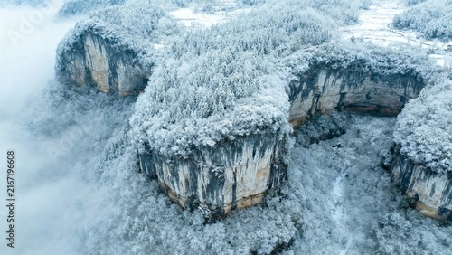 Snow-covered rock formations rising above misty clouds in a winter landscape
