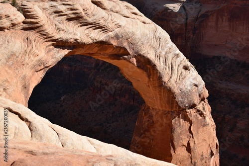 Natural sandstone arch formation in a desert landscape with eroded rock textures and shadows