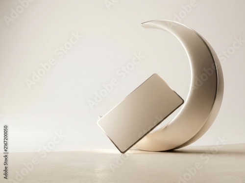 Gold credit card leaning against a modern abstract crescent sculpture on white background