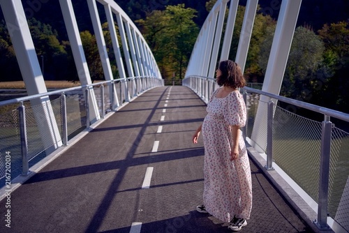 Foto Pregnant mature woman walking on modern white bicycle