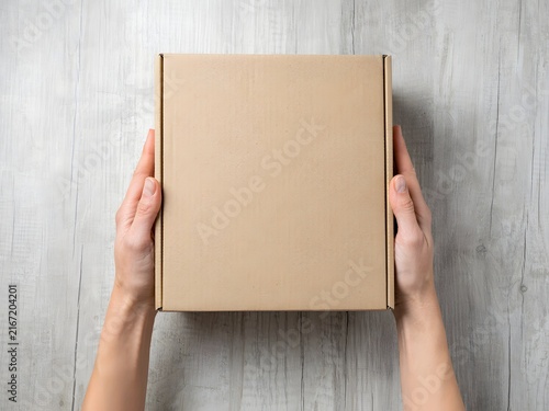 Hands holding empty cardboard box for packaging, shipping, or moving preparation