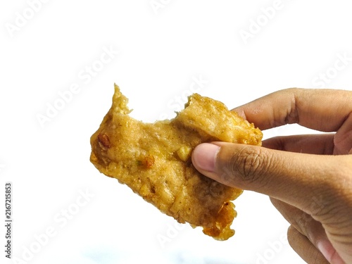 Фотография Hand holding a bitten crispy fried battered tempeh isolated on white background