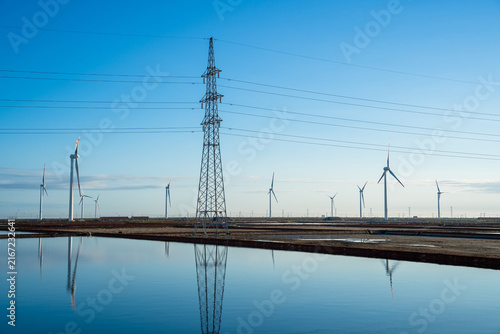 Wind Farm and Power Transmission Tower Under Clear Blue Sky