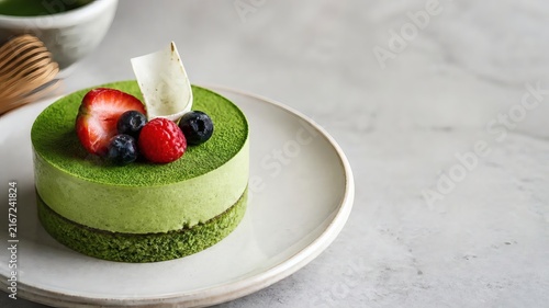 a sophisticated matcha mousse cake with small white chocolate decoration and fresh berries