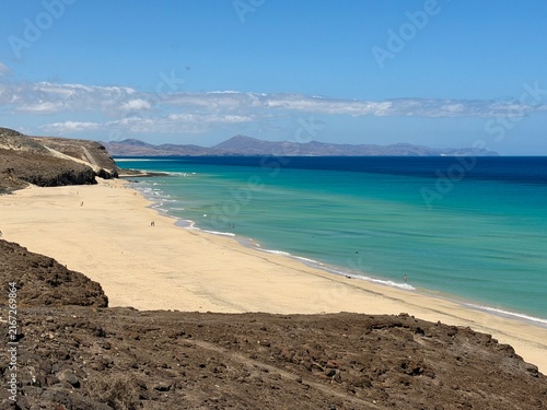 Canary Islands. Coastal landscape featuring a sandy beach and turquoise waters, with distant mountains visible under a clear blue sky