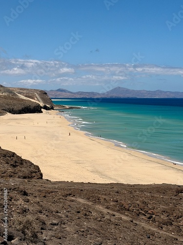 Canary Islands. Coastal landscape featuring a sandy beach and turquoise waters, with distant mountains visible under a clear blue sky