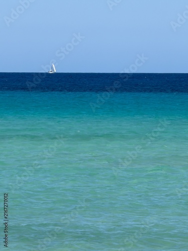 Canary Islands. Coastal landscape featuring a sandy beach and turquoise waters, with distant mountains visible under a clear blue sky