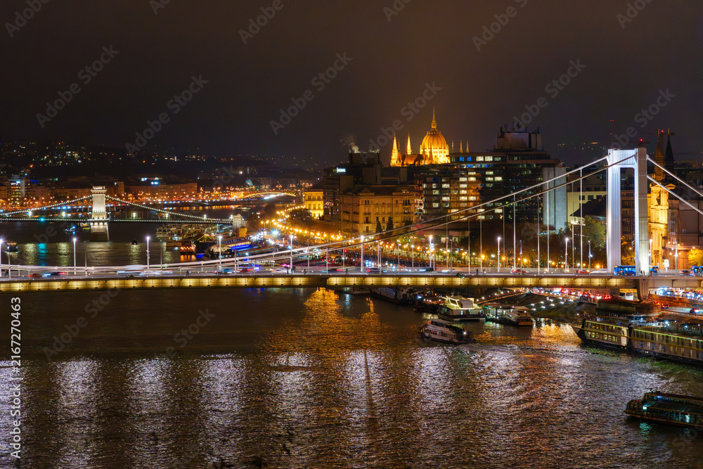 Fototapeta premium A breathtaking nighttime cityscape panorama of Budapest across the Danube river highlighting iconic historical architecture and illuminated modern bridge structures in Hungary
