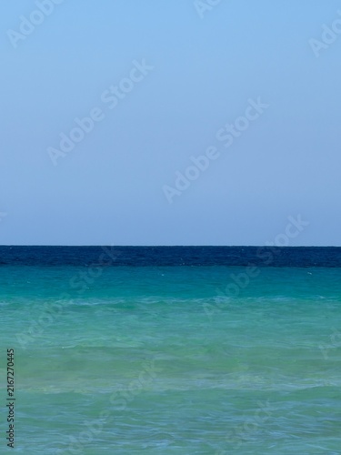 Canary Islands. Coastal landscape featuring a sandy beach and turquoise waters, with distant mountains visible under a clear blue sky