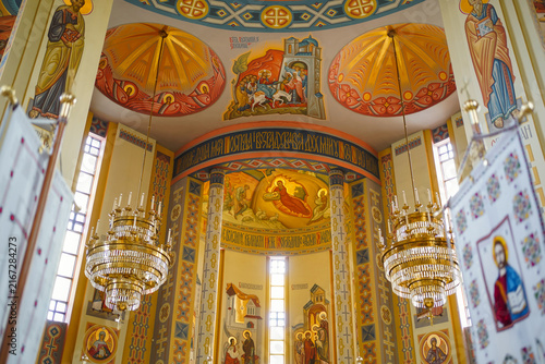 Fotografía Spacious church interior decorated with colorful frescoes, icons, golden chandeliers and intricate religious ornaments