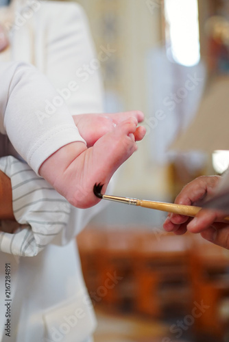 Cuadro en lienzo Priest performs the Christian rite of chrismation on a newborn during baptism, anointing the baby’s foot with holy oil
