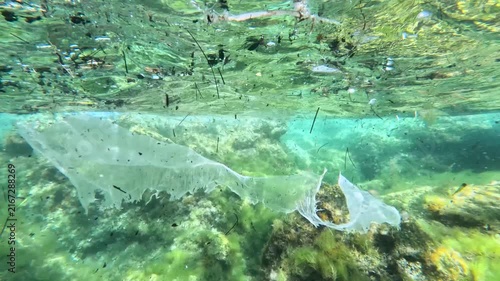 Plastic pollution and garbage floating in the sea captured with an underwater camera. Underwater view of plastic bags and ocean waste polluting the marine environment. Discarded trash and plastic garb