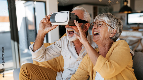 Senior couple enjoying virtual reality experience together, laughing and having fun with modern technology at home