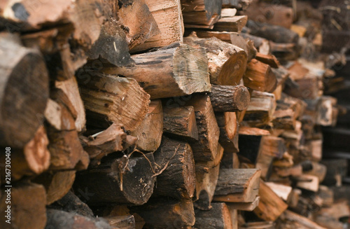 Firewood pile composed of split log prepared for cold winter season. Firewood texture with rough bark and circular cut surface forms natural backdrop, countryside lifestyle, heat production concept.