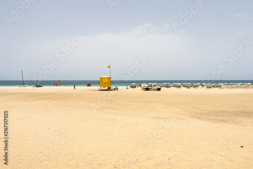 Sandy beach with lifeguard tower sun loungers and turquoise sea in Morro Jable, Fuerteventura.