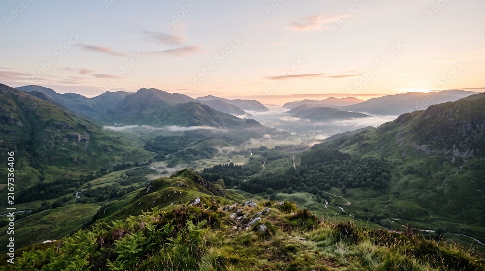 Fototapeta premium Serene mountain valley bathed in golden hour light with misty lowlands and rolling hills