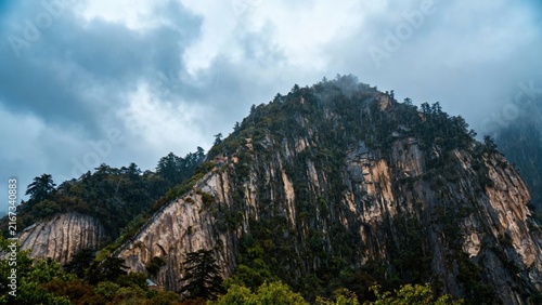 Majestic mountain peak covered in dense forest under a cloudy sky