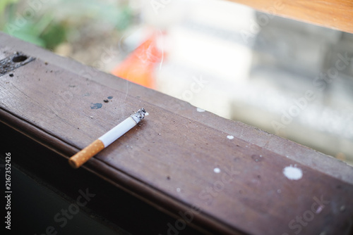 Extinguished cigarette on wooden windowsill