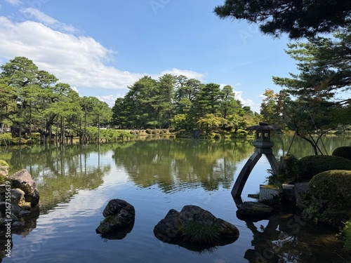 Foto Calm garden pond reflecting trees and sky