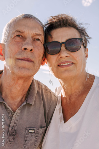 senior couple. Elderly man and woman in sunglasses calm, happy expressions. blue sky background, retirement lifestyle, long-term relationship, love, companionship, healthy aging, family values