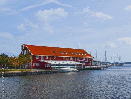 KRISTIANSAND, NORWAY - AUGUST 9, 2026: Sjøhuset Restaurant in a traditional red waterfront building beside a marina with boats and sailboats in central Kristiansand.