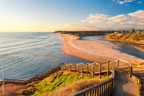 Beach access stairs at South Port overlooking the Onkaparinga River in South Australia. The coastal landscape combines sandy shoreline, river waters, and natural vegetation at sunset time