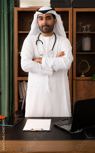 Bild auf Leinwand Middle-eastern doctor wearing emirati kandura working in the office - emirati do