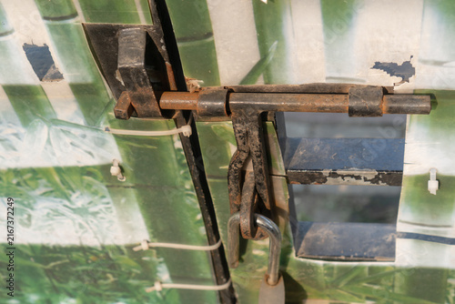 Konstfotografi rusty metal bolt latch on a printed bamboo pattern gate.