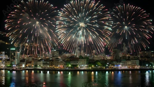 expansive cinematic 4K aerial panorama captures a year-end fireworks display in Valparaiso Chile with the bursts resembling glowing rain across the night sky and cityscape creating a spectacular