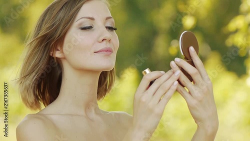 Young beautiful woman puts lipstick on lips
