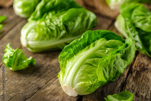 Fresh mini romaine lettuce hearts with crisp green leaves arranged on a rustic wooden table