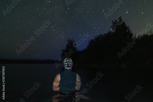 Foto Tactical diver wearing night vision goggles standing in lake water under starry