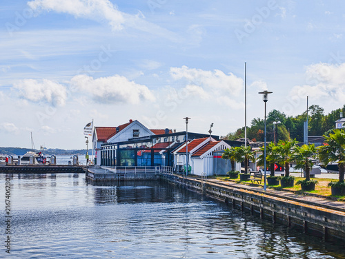 KRISTIANSAND, NORWAY - AUGUST 9, 2026: Waterfront marina with boats, traditional coastal buildings and a promenade in Kristiansand on a sunny summer day.