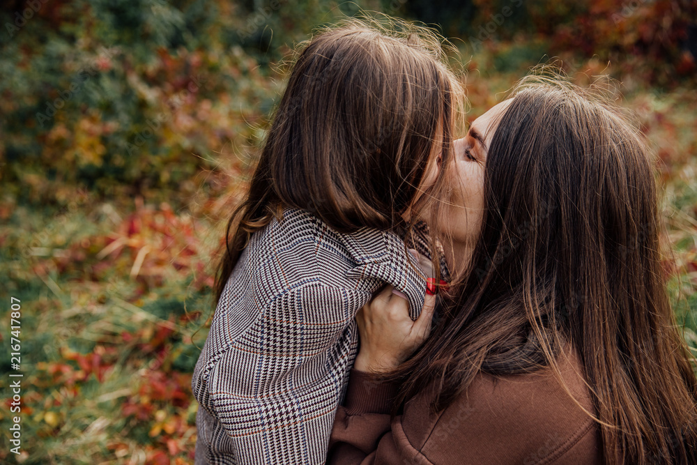 Fototapeta premium Mother and daughter share a tender moment in an autumn setting embracing the warmth of family love.