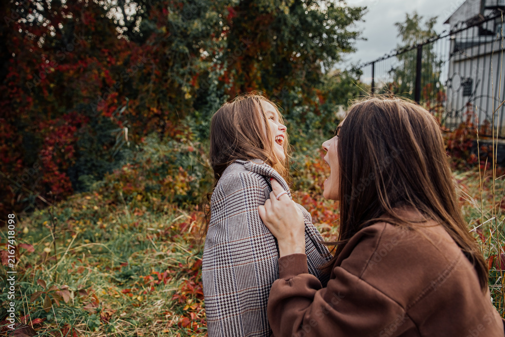 Fototapeta premium Joyful autumn moment between mother and daughter in a nature setting.